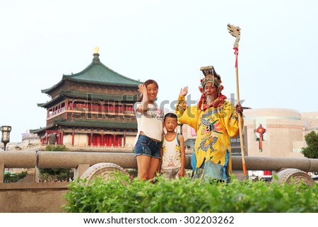 On July 29, 2015, xi 'an, in the clock tower scenic area, a wore a crown, dragon robe, a old man play the part of the emperor, in sorching burning sun, free and tourists.