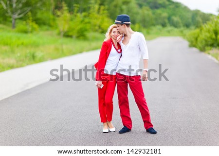 Happy loving couple in red and white suits on the road.