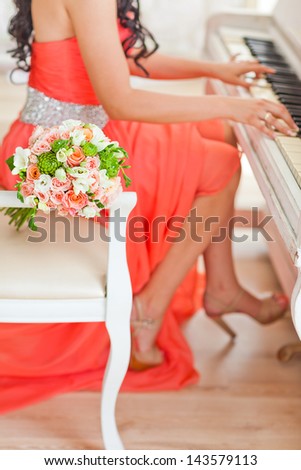 Wedding bouquet of flowers near the bride who plays the piano