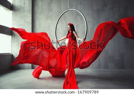 Beautiful pregnant woman acrobat in red long dress. Waving fabric. Fashion pregnancy.