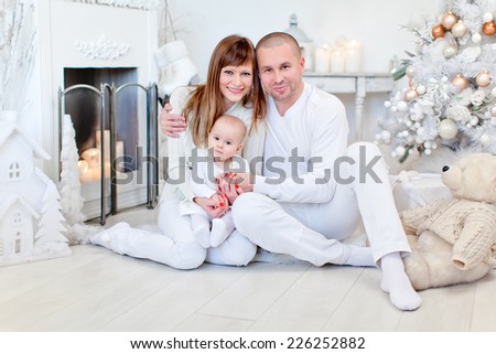 Photo of beautiful young family near the fireplace in design interiors. Christmas holidays.