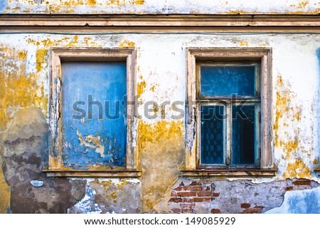 Old wall with two windows. The left window is only a frame on the wall.