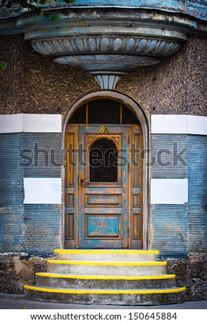 Entrance of beautiful old building. Steps with yellow stripes for blind people, door, part of balcony
