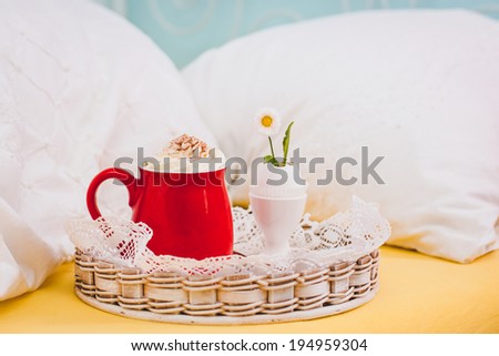 Breakfast in bed. Hot chocolate with whipped cream and little flower in eggshell. Selective focus.
