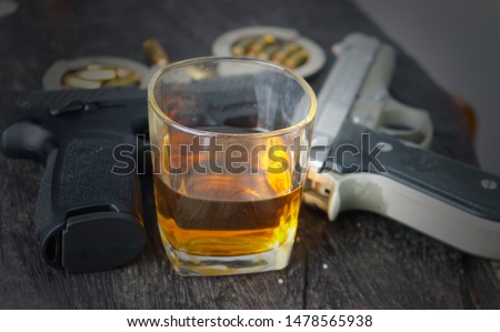 Glass of whiskey and gun.The relationship of alcohol and crime.