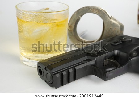 Glass of whiskey and gun.Concept of crime and alcohol relation.