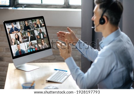Virtuak business meeting online. Successful businessman is negotiating with multiracial business partners on a video conference using a computer while sitting at his workplace