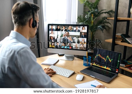 Virtual meeting, video call. Successful adult businessman have conversation with multiracial business colleagues by video call using a computer while sitting at his workplace
