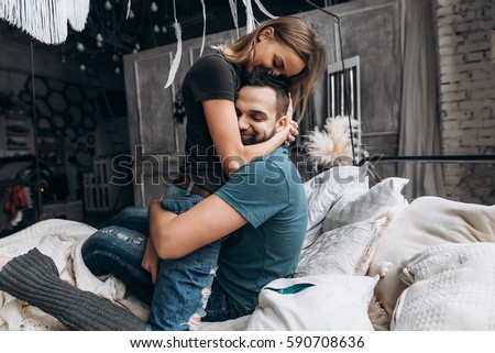 Photo of  Loving couple hug each other on the bed, in big bedroom. Love story, side view