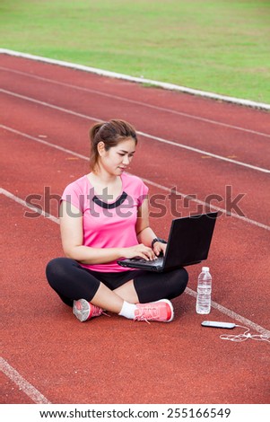 female runner using laptop computer on the running track and  bo