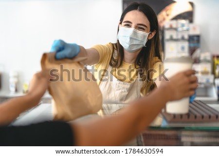 Bar owner working only with take away orders during corona virus outbreak - Young woman worker wearing face surgical mask giving takeout meal to customers - Healthcare and Food drink concept 