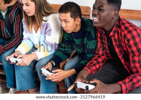 Young multiracial teenagers playing online video game console at home - Youth people addicted to new technology gaming entertainment Imagine de stoc © 