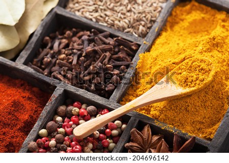 spices in box: pink black pepper, paprika powder, curry, bay leaf; anise; clove; cumin