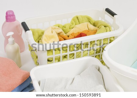 Wash colored laundry. Detergents and towels in white plastic basket, basket with colorful laundry to wash (handwash)