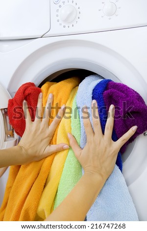 Woman loading clothes in the washing machine, Washing machine and colorful laundry to wash