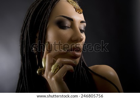Fashion Beauty. Mystic eastern Make-up. Beautiful Woman With Luxury glossy gold Makeup and stylish hair (dreadlocks) . Beautiful sensitive Girl Face, indian accessories (oriental jewelry)