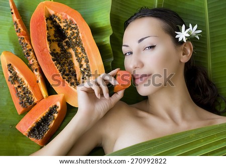 Sexy caucasian woman eating Fresh Papaya slices. Healthy exotic vitamin food (outdoors, tropical palm leafs background)