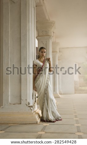 Beautiful young Indian Woman in Traditional Clothing with Bridal Makeup and Oriental Jewelry. Girl Bollywood dancer in Sari posing outdoor near the Eastern Palace. Eastern fairy tale