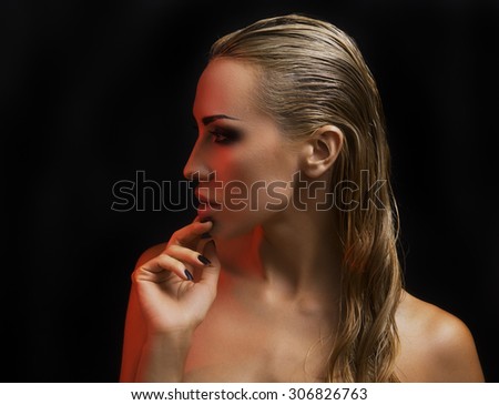 Portrait of Beautiful Young Sexy Blond Woman with Bright Make-up in Studio, profile. Dark Background. Smokey Eyes Makeup and Styled Long Hair