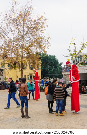 NAZARETH, ISRAEL - December 19, 2014: Santa Claus figures on stilts, local and visitors, in the square of the Greek Orthodox Church of Annunciation, in Nazareth, Israel