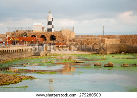ACRE, ISRAEL - MAY 04, 2015: Sunset scene of a Templar Fortress remains, lighthouse, restaurants, visitors and Haifa bay, in the old city of Acre, Israel