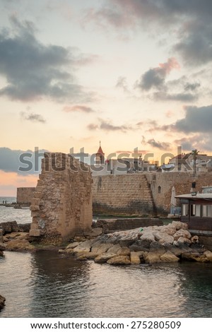ACRE, ISRAEL - MAY 04, 2015: Sunset scene of the old city walls, St. John the Baptist church and local fishermen, in the old city of Acre, Israel