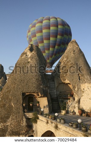 Cappadocia- Fairy chimneys house in Goreme. Hot Air Balloon comes out behind the Fairy Chimeys early in the morning - Turkey