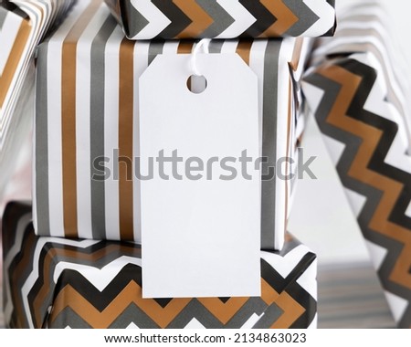 Present with blank vertical gift tag close up. Gift boxes wrapped in Striped and chevron geometric paper. Christmas, New Year, Birthday, Anniversary label mockup Stock foto © 