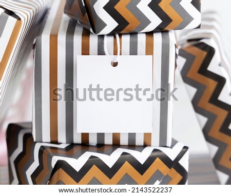 Present with blank square gift tag close up. Gift boxes wrapped in Striped and chevron geometric paper. Christmas, New Year, Birthday, Anniversary label mockup Stock foto © 