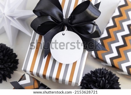 Present with round blank gift tag and black bow close up. Gift boxes wrapped in Striped geometric paper near black and white decor. Christmas, New Year, Birthday, Anniversary label mockup Stock foto © 