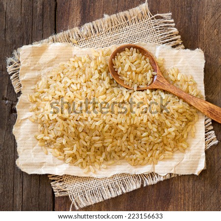 Unpolished rice with a spoon on a wooden table