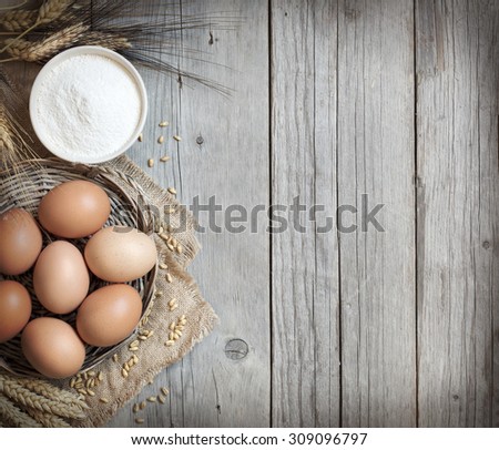 Chicken eggs, wheat and flour on the old wood