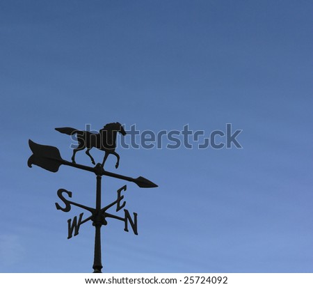 Rooftop weather vane against a clear blue sky.