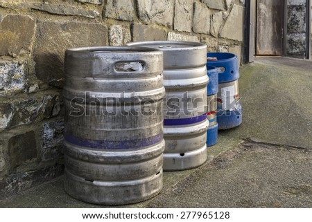 Silver coloured beer kegs, against a outside wall
