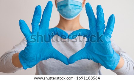 Woman with a medical mask and hands in latex glove shows the symbol of the heart. Doctor for the heart. Love to our pancreas. Love our medical professionals. 商業照片 © 