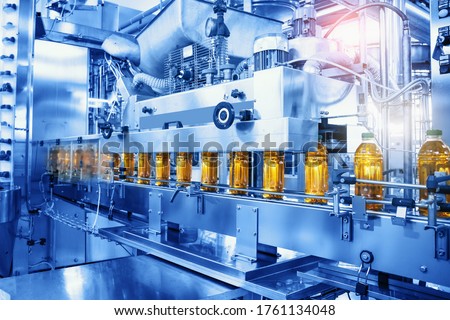 Beverage factory, Conveyor belt with juice in bottles, Industrial Interior in blue color, food and drink production line process.