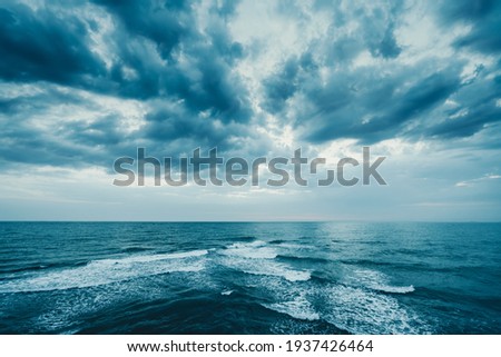Dark blue clouds and sea or ocean water surface with foam waves before storm, dramatic seascape