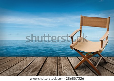 Director\'s chair on the wood and blue sea background