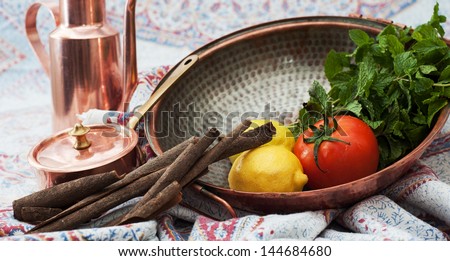 Fresh tomatoes, lemons and mint in brass bowl with cinnamon sticks