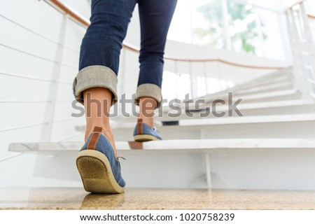 Young adult woman walking up the stairs with sun sport background. Сток-фото © 