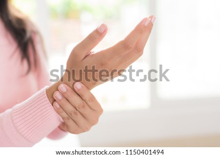 Closeup woman sitting on sofa holds her wrist hand injury, feeling pain. Health care and medical concept. 商業照片 © 