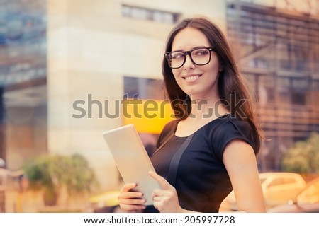 Young Woman with Tablet Out in the City - Woman wearing glasses, eyeglasses holding a PC tablet out in the city