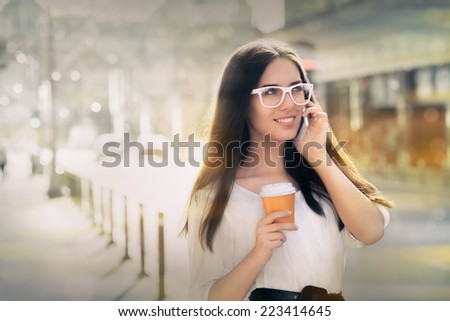 Young Woman with Coffee Cup on the Phone Out in the City - Woman smiling and talking on her phone holding a cup of coffee out in the city