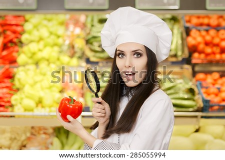 Funny Lady Chef Inspecting Vegetables with Magnifying Glass - Portrait of a young female cook in a grocery store checking for best quality ingredients