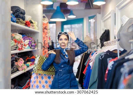 Curious Girl in Blue Trench Coat and Sunglasses Shopping - Surprised retro young woman in a raincoat in a clothing store