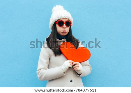 Heartbroken Sad Upset Girl Holding a Heart on Blue Background. Girl feeling blue sad after breakup in time for Valentine’s Day 
 ストックフォト © 