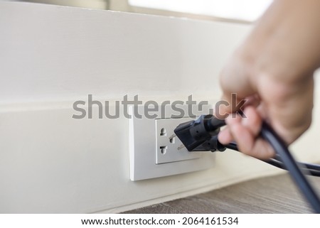 In the hand of a young man holding a power cord to unplug unused appliances to save energy, save money. Foto stock © 