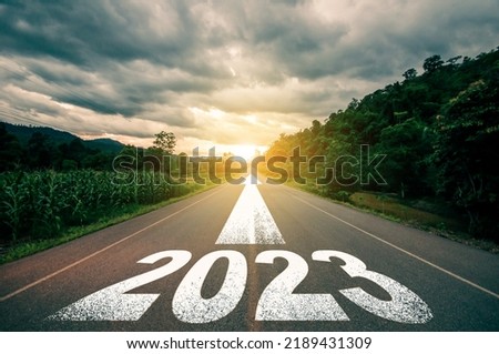 Photo of New year 2023 or straight forward concept. Text 2023 written on the road in the middle of asphalt road with at sunset. Concept of planning, goal, challenge, new year resolution.
