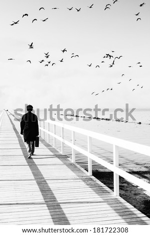 man walking on pier with bird flying