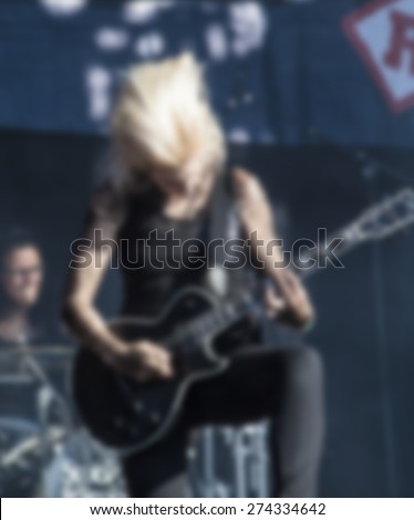 woman playing rock guitar on concert,blurred rock background
